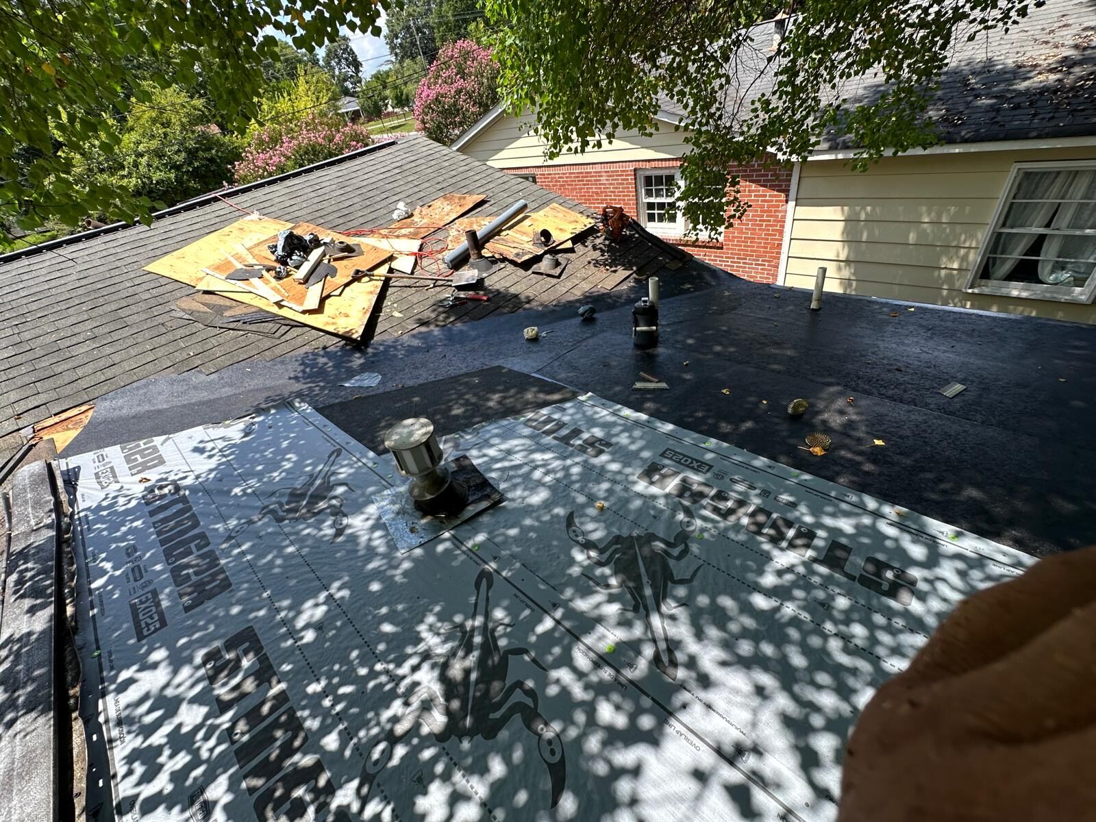 Roof repair in progress with new decking, a sealed low-slope section and synthetic underlayment